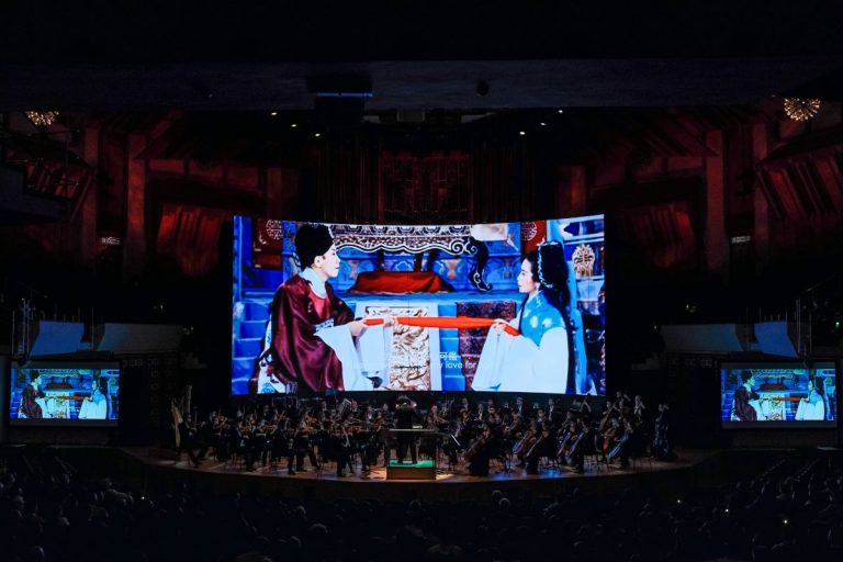《落花滿天．管弦光影之旅──帝女花65週年跨界創意》嘗試將重新剪接的任白《帝女花》電影和唱片選段與新作的管弦樂融合起來。樂團在播放着影音的大屏幕前現場演奏，兩邊加設較小的屏幕同步播放，照顧左右兩側的觀眾。（相片提供：Ka Lam∕香港管弦樂團）